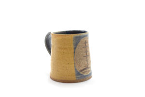 A handcrafted mug that is yellow with a blue front and handle. In the middle of the blue front is a brown circle with a hand-drawn tree inside.