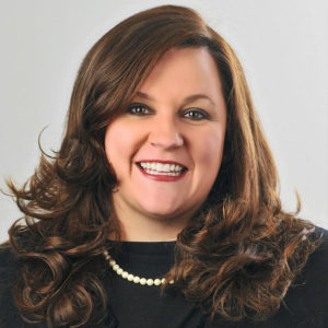Headshot of Kim Davis, woman with brown hair wearing a black shirt and pearls