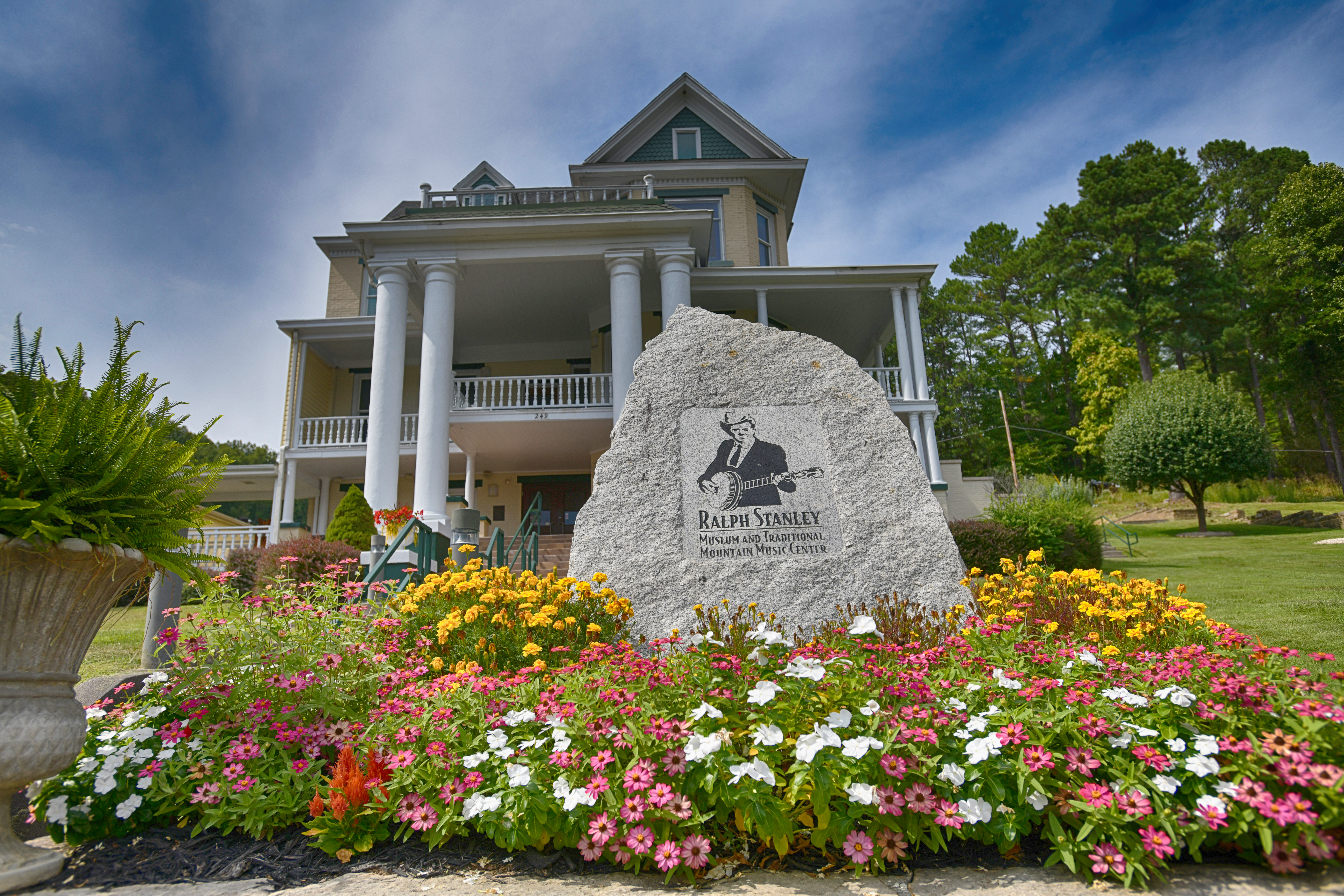 outdoor photo of the Ralph Stanley Museum with a blue sky and blooming flowers in front