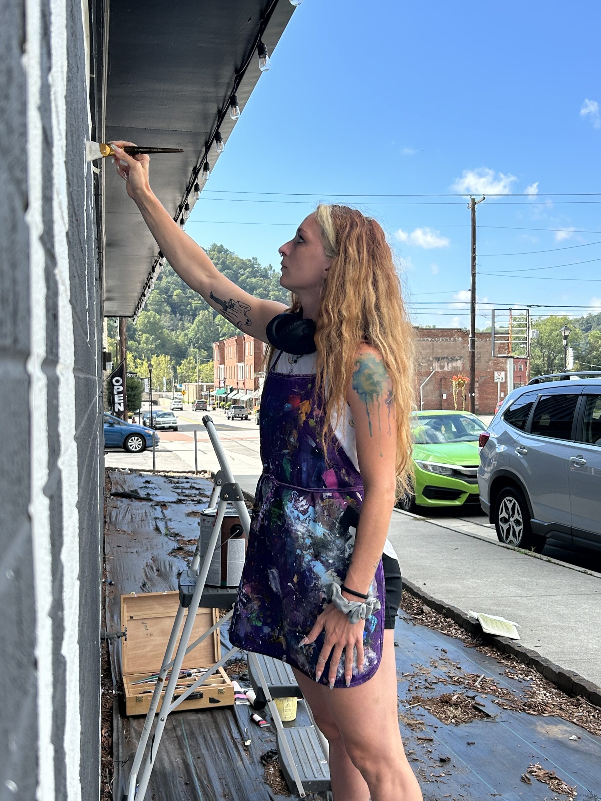 Kandee Wallace painting a LOVE mural in St. Paul on gray building.